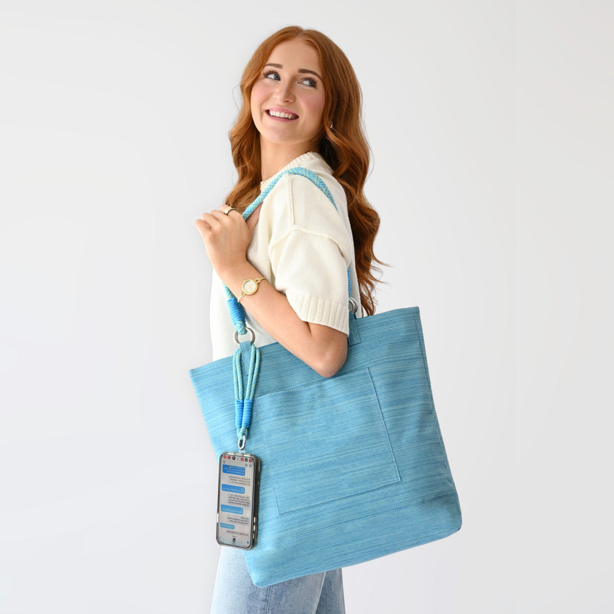 Woman holding a light blue Active Tote bag with shoulder strap and phone holder