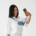 Woman wearing a blue Clip & Go vegan leather crossbody phone pouch with adjustable strap