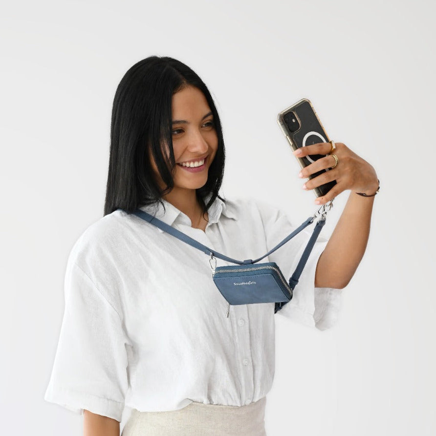 Woman wearing a blue Clip & Go vegan leather crossbody phone pouch with adjustable strap