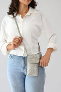 Woman wearing a white button-up shirt and light blue jeans carrying a cream floral jacquard tote bag with matching pouch and keychain.